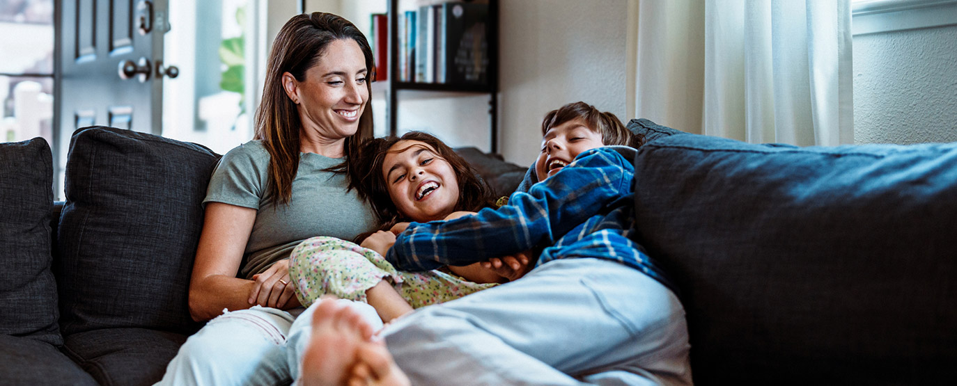 Smiling family laying on a couch together.