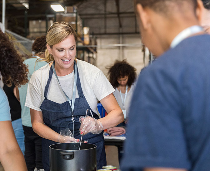 Person serving food at a community kitchen.