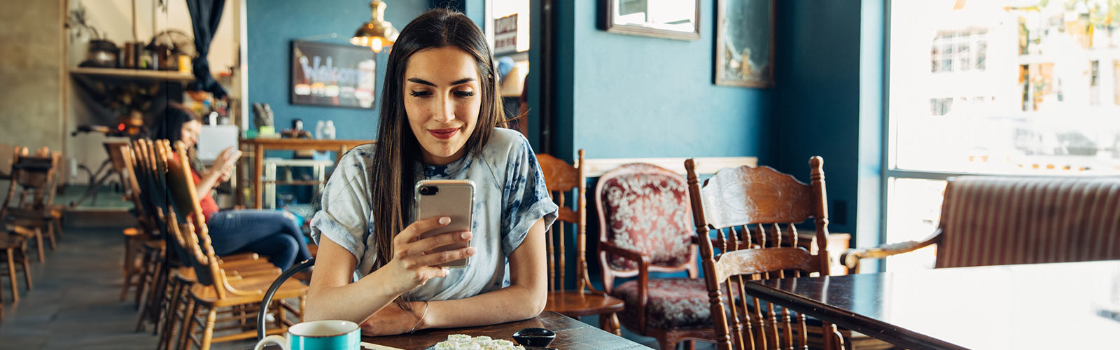 Person banking on their phone in a cafe.