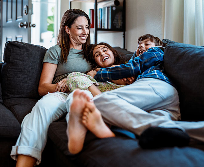 Family laughing and cuddling on their couch.